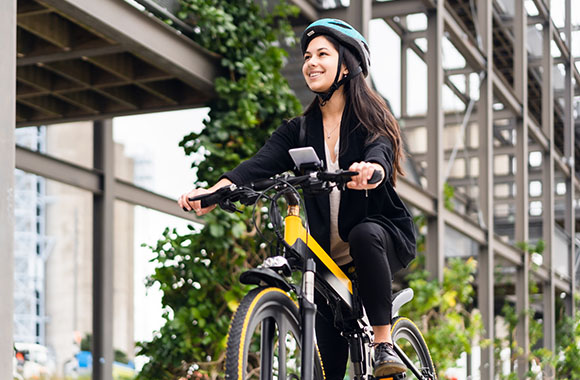 Kobieta na rowerze typu pedelec przemierza miasto.