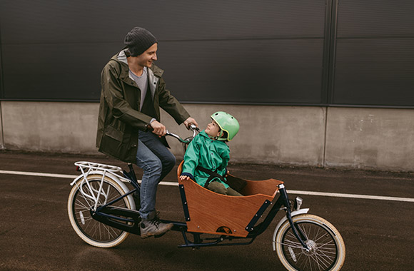 Tata przewozi syna na rowerze cargo.
