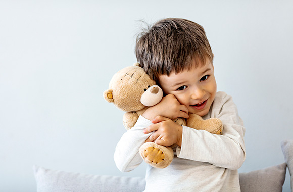 Kinderspielzeug – Junge kuschelt mit seinem Teddy.