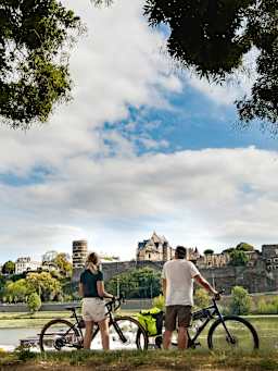 La Loire à vélo : deux cyclistes profitent de la vue sur le château d’Angers lors de leur rando vélo.