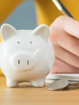 Geld sparen - vrouw houdt haar budget bij in een notitieboekje.