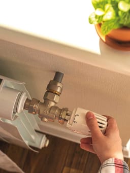 Besparen op verwarmingskosten - vrouw regelt de verwarming.