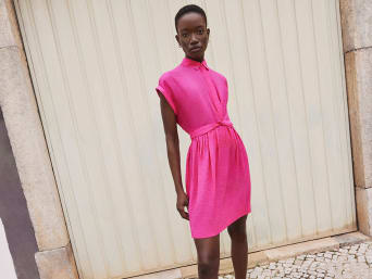 Woman in a short pink shirt dress stands in front of a garage door | C&A