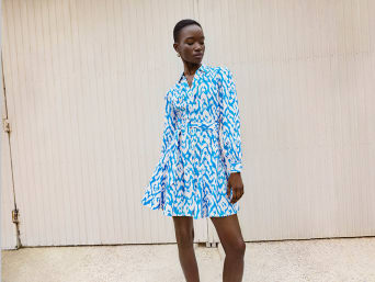 Woman in a blue and white patterned fit & flare dress stands in front of a garage door | C&A