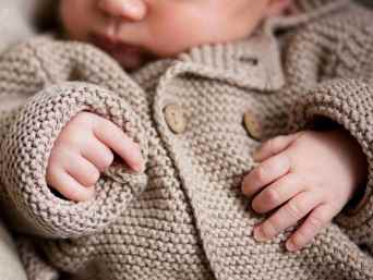 Schlafendes Baby in warmer, beiger Wolljacke