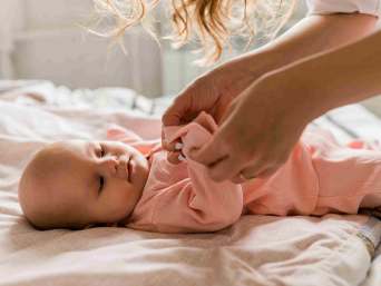 Baby wird mit Babykleidung für den Frühling angezogen