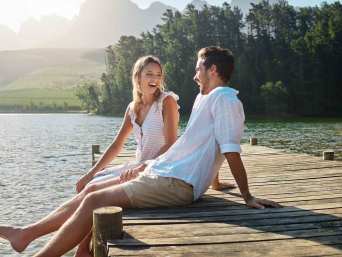 Date-Outfits: Mann und Frau sitzen auf einem Steg am Wasser. Date-Outfits: Mann und Frau sitzen auf einem Steg am Wasser.