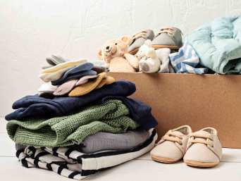 Stapel Kinderkleidung mit Schuhen und Kuscheltieren