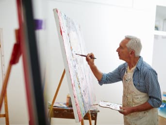 Une personne âgée fait de la peinture comme activité manuelle.