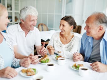 Des amis retraités discutant autour d’un repas léger et sain.