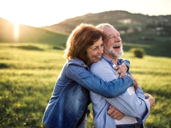 Smějící se manželský pár v důchodu na louce.