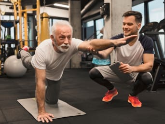 Sport voor senioren: Oudere man traint met een personal trainer in de sportschool.