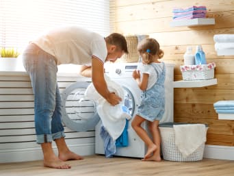 Een overhemd wassen - vader en dochter vullen de wasmachine met overhemden.