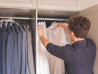 Pranie koszul: mężczyzna wybiera czystą białą koszulę ze swojej szafy.