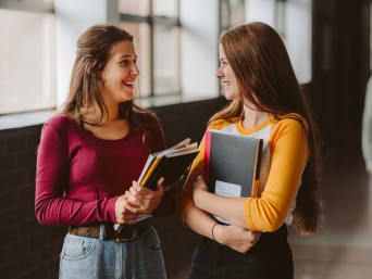 Intercambio de opiniones sobre las agencias de intercambio: dos estudiantes hablan entre sí en el pasillo de un centro educativo.