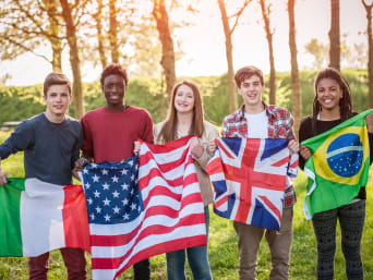 Zalety i wady wymian szkolnych: Grupa międzynarodowych uczniów z flagami państw.