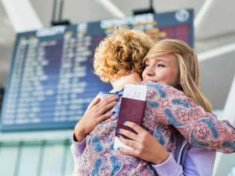 Planowanie roku szkolnego za granicą – mama z córką żegnają się na lotnisku.