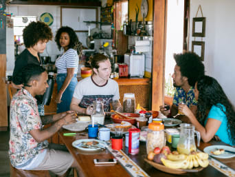 Beneficios de viajar y trabajar: varios jóvenes desayunando juntos en un hostal. 