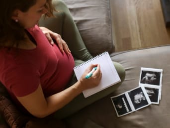 Schwangere Frau schreibt eine Liste mit möglichen Babynamen.