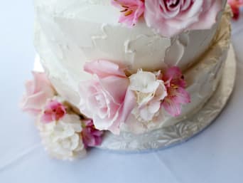 Een witte taart met roze bloemen gedecoreerd.