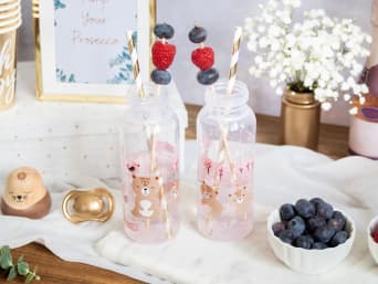 Mocktails - rosa Limonade mit Beeren und Blüten in einer Babyflasche.