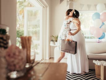 Une femme remet le cadeau de la baby shower à la future maman lors de son arrivée.