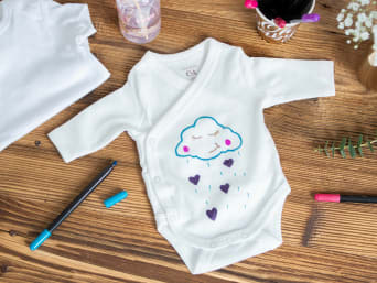 Painting baby clothes at a baby shower.