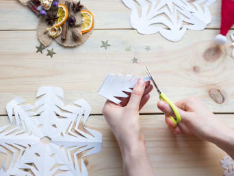 Sneeuwvlokken maken - Kind maakt sneeuwvlokken van papier.