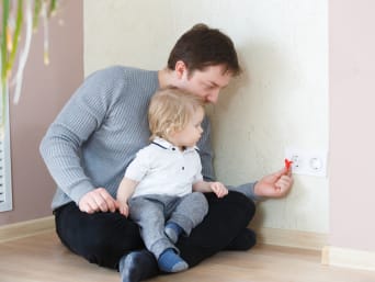 Kinderveilig maken van de flat - Vader beveiligt het stopcontact met een beschermer.
