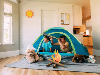 Activité d’intérieur : des enfants jouent au camping dans le salon.