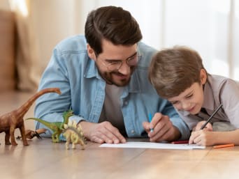 Spiele für Kleinkinder: Vater und Sohn spielen mit Dino-Figuren.