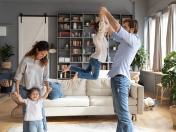 Bewegungsspiele: Familie tanz ausgelassen im Wohnzimmer.