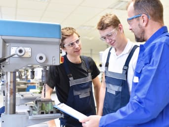 Stage pratique : un tuteur explique aux jeunes en stage lycée professionnel comment fonctionne une perceuse.