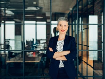 Bewerbungsgespräch Outfit – Frau im seriösen Business-Outfit steht in einem hellen Büroraum.