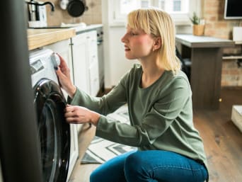BH richtig waschen in der Waschmaschine: Frau wählt ein schonendes Waschprogramm aus.