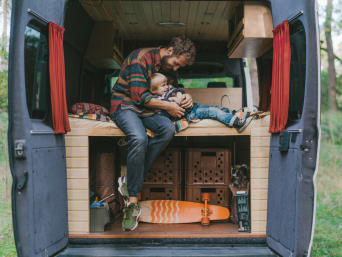 Camping dla dzieci – synek beztrosko bawi się z tatą w samochodzie kempingowym.