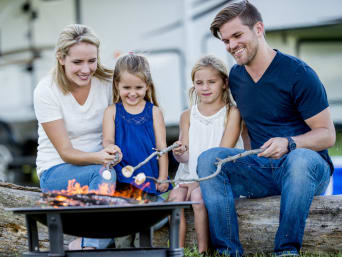 Camping mit Kindern – Familie röstet zusammen Marshmallows.