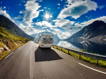 Vacanze ecosostenibili - Camper viaggia su una strada in mezzo alle montagne.