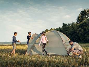 Zelten mit Kindern: Familie baut ein Zelt auf.