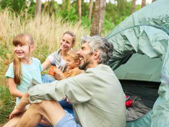 Camping mit Kindern: Familie bei einem Zelturlaub. 