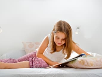 Comics lesen – Mädchen liest einen Comic auf ihrem Bett.