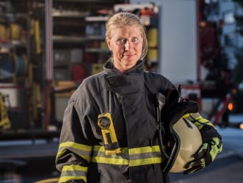 Voorwaarden vrijwillige brandweer: vrouw in brandweerkleding. 