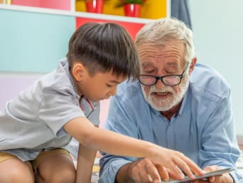 Voluntariado en educación infantil: un hombre jubilado hace de mentor de lectura de un niño. 