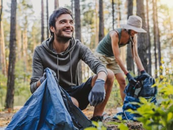 Tipos de voluntariado: una pareja participa en una recogida de basura en un bosque.