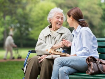 Zaangażowanie społeczne – kobieta rozmawiająca z seniorką w parku. 