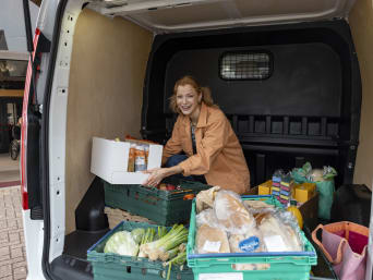 Ehrenamt Tafel – Freiwillige räumt Lebensmittel aus dem Auto aus.