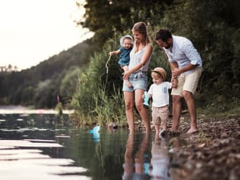 Unternehmungen mit Kindern: Familie erkundet ein Flussufer.