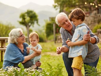 Urlaub mit Enkelkind: Großeltern erkunden die Pflanzen im Garten mit ihren Enkelkindern.