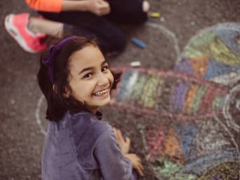 Tipps gegen Langeweile: Mädchen malt mit Kreide einen großen Schmetterling auf den Boden.