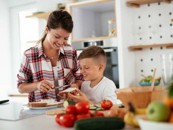 Prepararsi al campo estivo – mamma e figlio preparano insieme la colazione.